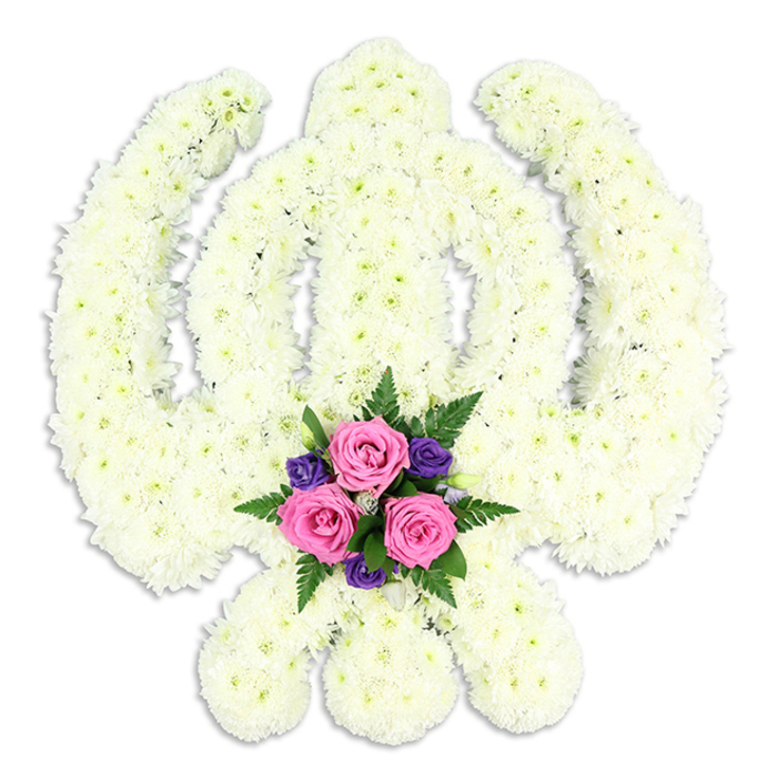This image presents a beautifully crafted Sikh Khanda floral tribute, photographed cleanly against a pure white background so the form appears to almost float in space. The symbolic shape-central Khanda sword, circular Chakra, and the two crossed Kirpans that sweep outward-is constructed entirely from small white chrysanthemums, each bloom placed shoulder to shoulder in a continuous carpet of petals. From a short distance, the flowers blend into a single, velvety surface, yet on closer inspection you can almost trace individual petals curling delicately at their tips. The florists have followed the contours of the Khanda with painstaking care, ensuring the circle remains perfectly round and the sword blades taper to a neat point, a precision that reflects both artistic pride and deep respect for Sikh tradition. The lighting is soft and even, casting a faint shadow beneath the lower curve to give the arrangement depth, as if it is gently lifted from the background. At the very base, where the two Kirpans cross, a compact focal bouquet introduces colour and emotion. Three soft pink roses, at that lush stage between bud and full bloom, nestle together with their petals layered in gentle spirals. Around them, small deep purple flowers-likely lisianthus or freesia-add notes of rich, contemplative colour. Lacy green fern fronds and glossy leaves frame the cluster, creating a natural cradle of foliage. The overall effect is dignified yet tender, a tribute that might be chosen by a family in Garston to honour a loved one at a Sikh funeral, memorial gathering, or prayer service. It feels rooted in faith and community, like something you might see delivered to a gurdwara or family home near Garston Park or along St Mary's Road, carrying with it quiet comfort and a sense of spiritual peace.