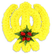 A carefully crafted floral tribute forms the sacred Khanda emblem against a clean white backdrop, its silhouette defined by thousands of small, tightly packed bright yellow chrysanthemum blooms. The arrangement reads like a textile of petals: the circular chakram, the two curved kirpans crossing below, and the upright, double-edged khanda in the centre are all modelled in the same sunny yellow, the dense heads of chrysanthemum creating a soft, sculpted surface that catches light and shadow to give the emblem a gentle three-dimensional presence. At the very heart of the chakkar sits a compact cluster of deep red roses - five rich, velvety buds - nestled into a collar of dark green fern fronds; this vivid crimson core anchors the composition and offers a quiet, respectful contrast to the jubilant yellow. The ferns' glossy, feathered texture frames the roses and adds a cooling, natural edge to the warm palette. A faint grey shadow beneath the piece confirms it as a freestanding tribute, photographed in soft, neutral light that leaves colour and form true to life. The scent one might imagine is mild and floral, a soft chrysanthemum sweetness underscored by the heady, velvet note of rose. This tribute reads as both symbolic and personal: suitable for a Sikh remembrance or a ceremonial display where faith and honour are expressed visually. As a local florist with deep ties to Garston's community, I picture this placed respectfully at a gurdwara entrance or beside a commemorative lectern, its colours speaking of remembrance, dignity and the care taken in hand-assembling each bloom.