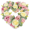 A delicately composed heart-shaped floral tribute stands out against a crisp white background, its soft colours and dense texture creating an immediate sense of comfort and care. The heart is fully formed by a generous mix of pastel blooms, with creamy ivory and light lemon-yellow roses placed as anchor points throughout the design. Their velvety petals spiral tightly in the centre and then unfurl gently, giving the arrangement a feeling of quiet elegance. Enfolding these roses are numerous light pink carnations, their frilled, layered petals adding a billowing, almost cloudlike softness that fills the heart without any empty spaces. Interspersed among them, deeper rose-pink and mauve lisianthus blossoms introduce a richer, twilight hue and a more open, cup-like shape, which adds variety and a sense of gentle movement. Threaded all around are sprays of silvery eucalyptus, the cool green leaves with their rounded form creating a serene backdrop and clearly tracing the heart's outline. Tiny yellowish-green buds nestle between petals, suggesting new growth and freshness. The flowers are arranged tightly together, giving the wreath a lush, substantial presence that feels both tender and dignified. The overall tone is one of love, remembrance, and quiet support, ideal for expressing condolences or marking a memorial. Imagined in the hands of a skilled Garston florist, this heart would be a fitting choice for a funeral service, a tribute at a local chapel near Garston Park, or a sympathy arrangement delivered to a grieving family, offering a gentle, visual expression of care when words are hard to find.
