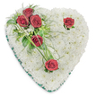 A tender, heart-shaped memorial made entirely from a soft cushion of pristine white chrysanthemums sits photographed against a clean white background, its surface almost cloud-like in texture. The chrysanthemum heads are densely set so that each tiny bloom nests into the next, producing a seamless, tranquil plane that reads as purity and quiet comfort. From the upper left comes a thoughtful diagonal cluster of deep crimson roses - three blooms gathered close together among glossy green leaves and delicate fern-like fronds - their velvety petals opening to reveal rich, sombre colour that contrasts with the white base. Two additional red roses are placed with care: one near the upper right curve of the heart and a single bloom toward the bottom point, each given a few spare green accents and slender, arcing blades of bear grass to add a graceful line and movement. A narrow emerald-green satin ribbon neatly trims the heart's edge, giving a subtle frame and a touch of formality without distraction. The lighting is soft and even, casting gentle shadows that emphasize the arrangement's depth and the tactile quality of the blooms; one can almost sense the faint, comforting scent of roses layered over the lighter green perfume of ruscus and fern. This classic sympathy wreath reads as an expression of enduring love and respect - the combination of white and red signalling remembrance and heartfelt sorrow - and is suited for funeral services, memorial tributes, or any setting where quiet consolation is needed across Garston and the surrounding neighbourhoods.
